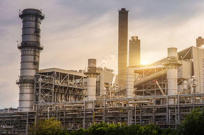 Low angle view of factory against sky during sunset