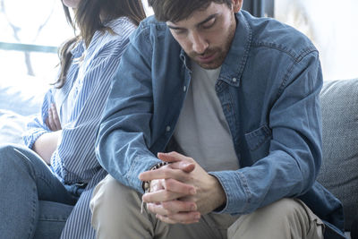 Side view of man using mobile phone while sitting on sofa at home
