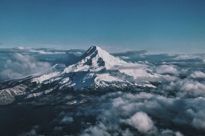 Aerial view of snowcapped mountains against blue sky