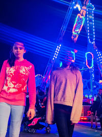 Full length of woman standing against illuminated lights