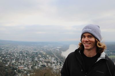 Portrait of smiling man standing in city against sky