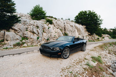 Car on road amidst rocks against sky