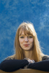 Portrait of young woman with long blond hair against sky