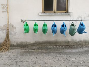 Watering cans hanging on rod against wall