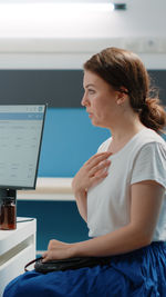 Side view of young woman using laptop at office