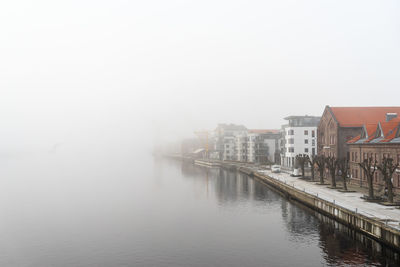 River by buildings in city against sky