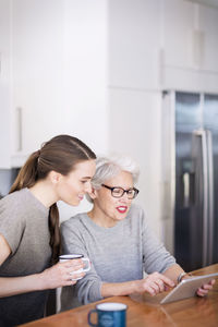 Mother and daughter looking at tablet computer while sitting at home