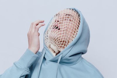 Young man wearing hooded shirt standing against white background