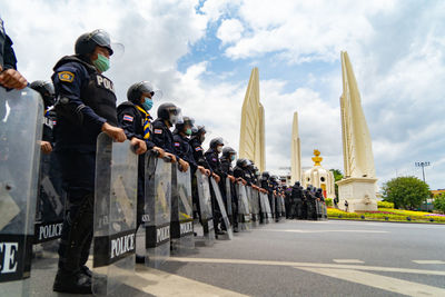 Rear view of people standing against sky in city