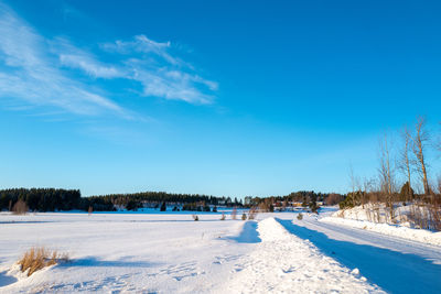 Snow covered field against blue sky