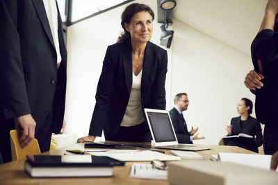 Smiling female professional looking at colleagues during meeting in law firm