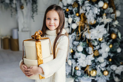 Portrait of smiling girl standing on snow during christmas