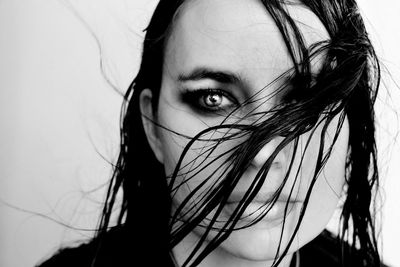 Close-up portrait of beautiful woman with wet hair against white background
