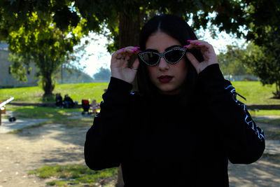 Portrait of woman wearing sunglasses standing by plants