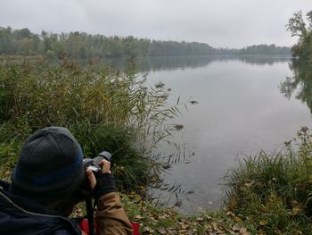 Man photographing by lake