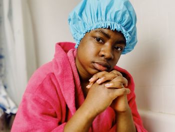 Close-up portrait of young woman wearing shower cap while sitting in bathroom