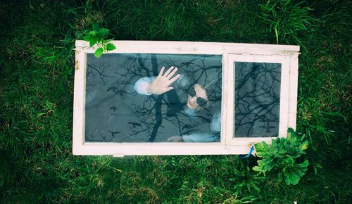 High angle view of woman seen through window frame at field