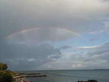 Scenic view of rainbow over sea against sky