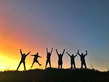 Silhouette friends against sky on field during sunset