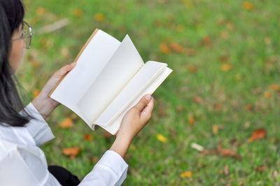 Midsection of woman reading book on field