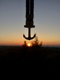 Close-up of silhouette cross on field against sky during sunset