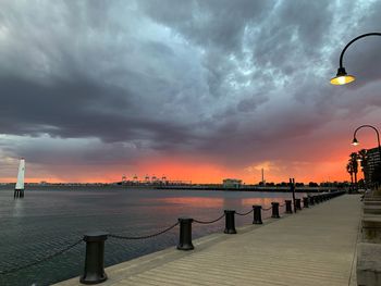 Street by sea against sky during sunset