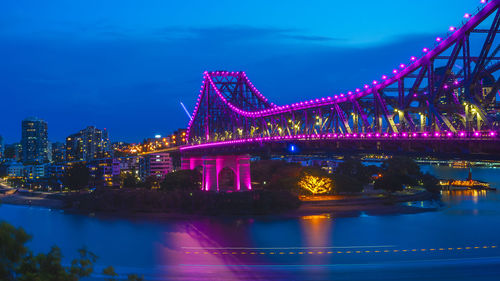 Illuminated suspension bridge over river at night