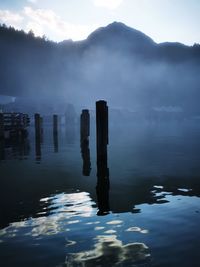 Wooden posts in sea against sky