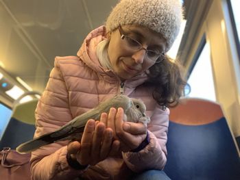 Low angle view of woman holding bird while traveling in train