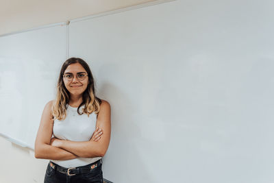 Portrait of young woman standing against wall