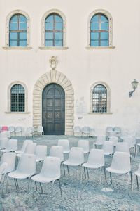 Empty chairs and tables against building