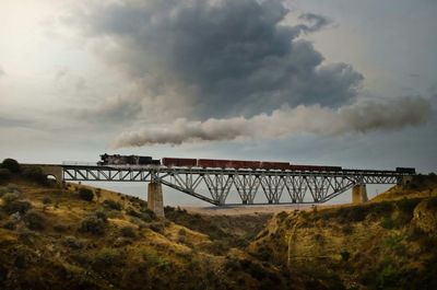 Bridge over sea against cloudy sky