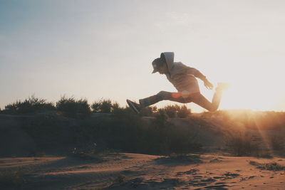 Man jumping by tree against sky