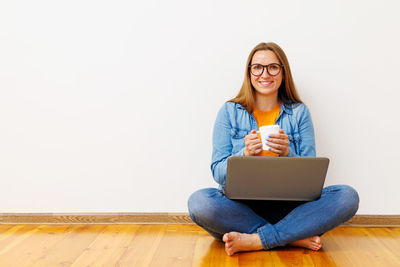 Young woman using laptop while sitting on table