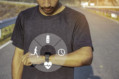 Midsection of man holding camera while standing outdoors