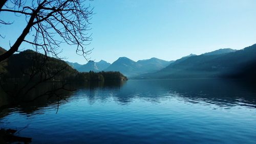 Scenic view of lake and mountains against clear blue sky