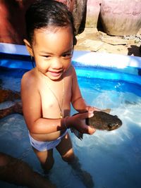 High angle view of shirtless girl holding fish in swimming pool