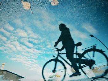 Silhouette man riding bicycle on street