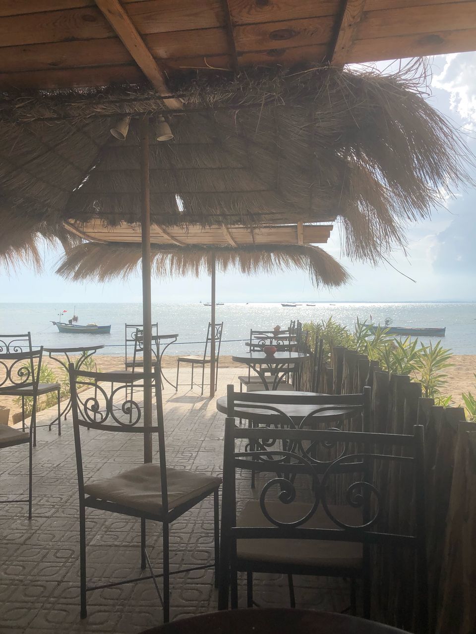 architecture, nature, sky, no people, roof, water, plant, day, sea, built structure, railing, beach, tree, thatched roof, outdoors, sunlight, chair, tropical climate, palm tree, horizon over water