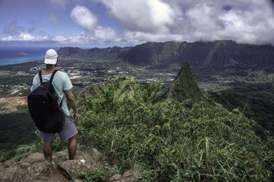 Rear view of man standing on mountain against sky