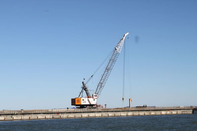 Cranes at construction site against clear blue sky