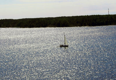 Sailboat sailing on lake against sky