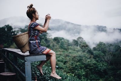 Full length side view of woman sitting on rock