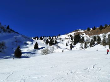 Snow covered landscape against clear blue sky