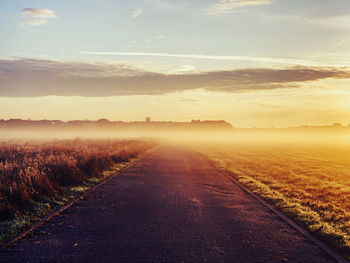 Empty road along landscape during sunset