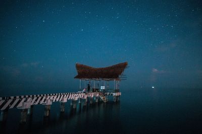 Lifeguard hut in sea against sky at night