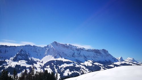 Scenic view of snowcapped mountains against clear blue sky