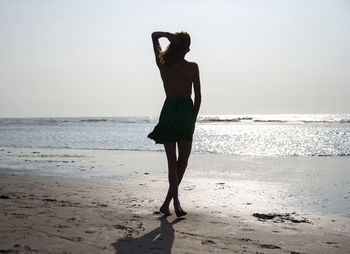 Rear view of woman standing at beach