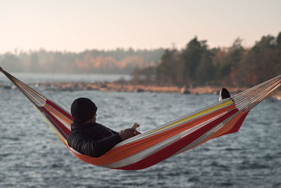 Man resting in hammock by lake