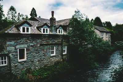 House amidst trees and buildings against sky
